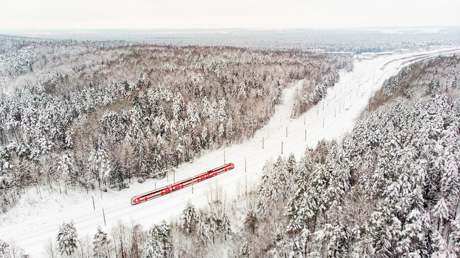 Litauische Eisenbahn LTG setzt auf IVU.rail Zug aus der Vogelperspektive in einem schneebedeckten Waldgebiet
