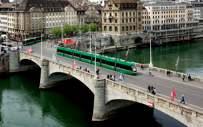 Grüne Straßenbahn auf einer Brücke über einem Fluss in Basel