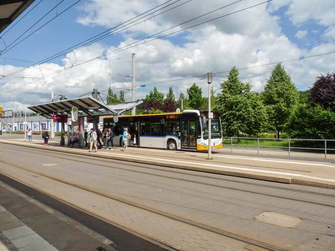Bus an einer Bushaltestelle mit einsteigenden und aussteigenden Fahrgästen