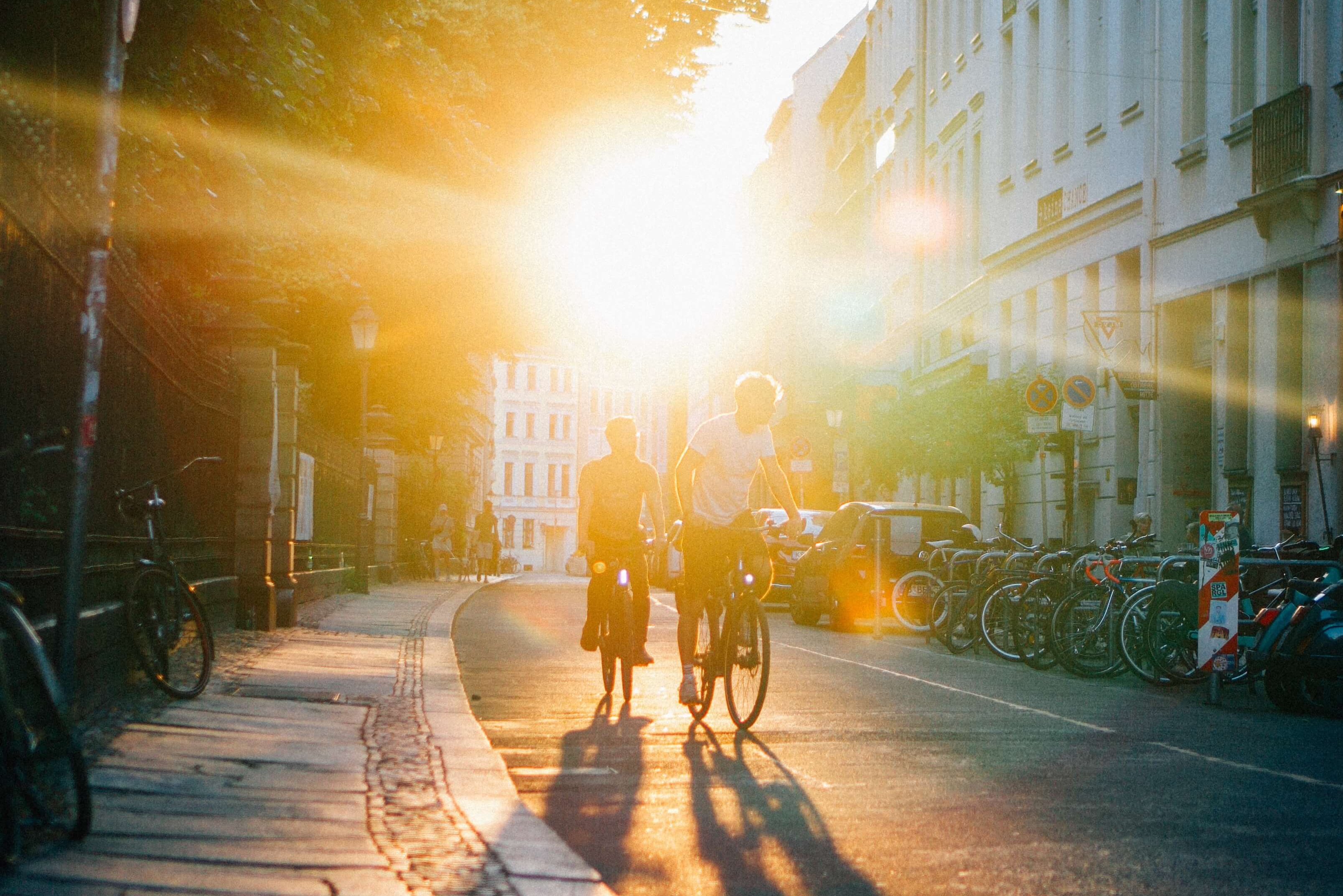 Zwei Fahrradfahrer fahren bei Sonnenuntergang die Straße entlang
