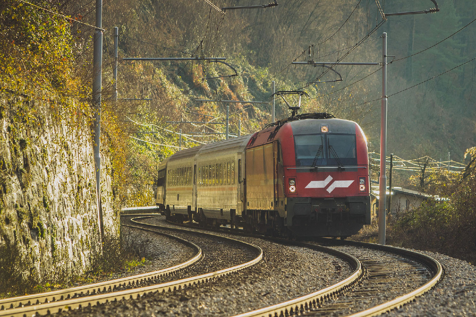 Rote SŽ Eisenbahn vor grün bewachsenen Bergen