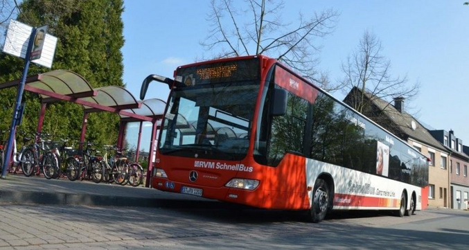 Bus der WVG an einer Bushhaltestelle mit Häusern und Fahrrädern im Hintergrund aus der Froschperspektive