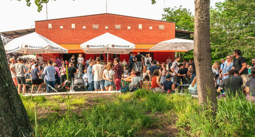 Menschen auf einem Sommerfest im Park vor einem Imbisshaus