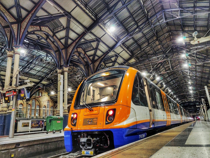 Ein orangener Zug von Arriva Rail London steht in einem Londoner Bahnhof.