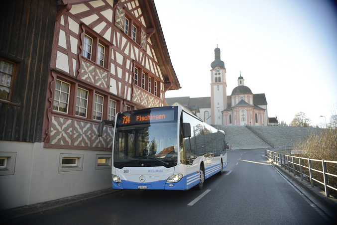 Ein blau-weißer Bus vor einem Kloster in der Innenstadt.