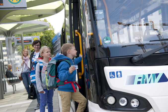 Schulkinder steigen in einen rms Bus an der Bushaltestelle ein