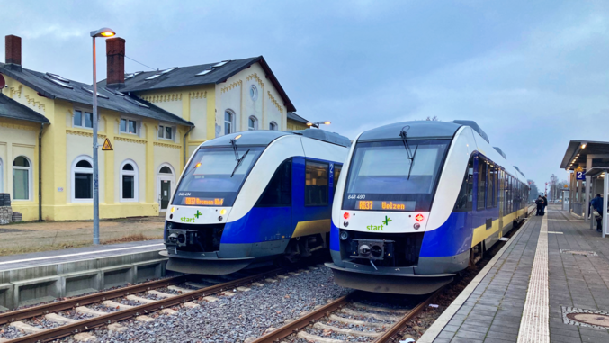 Zwei blau-weiße Züge von start stehen an einem Bahnhof.